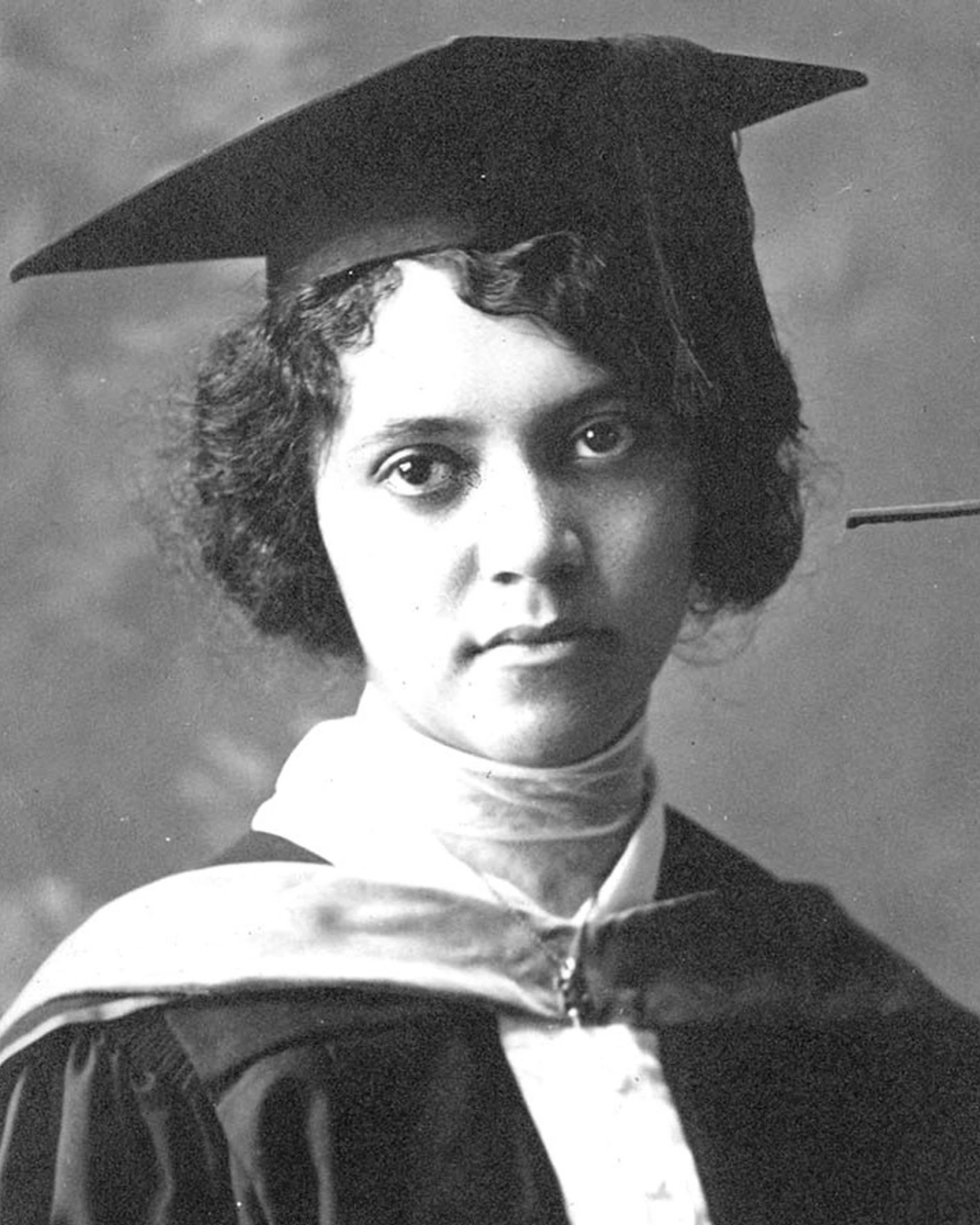Alice Augusta Ball facing the camera in a dark academic gown, light hood, and mortarboard.