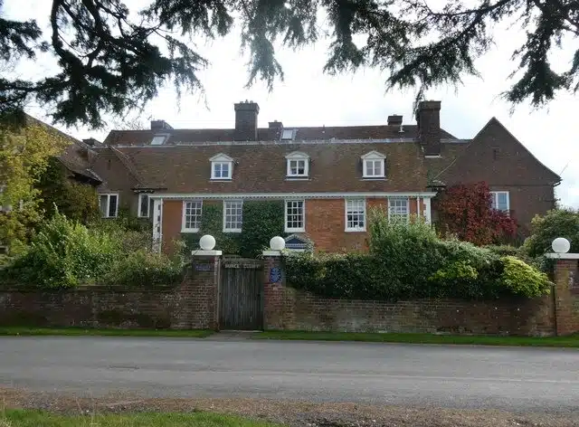 Red-brick Bunce Court house behind a garden wall and a gate bearing the name Bunce Court.