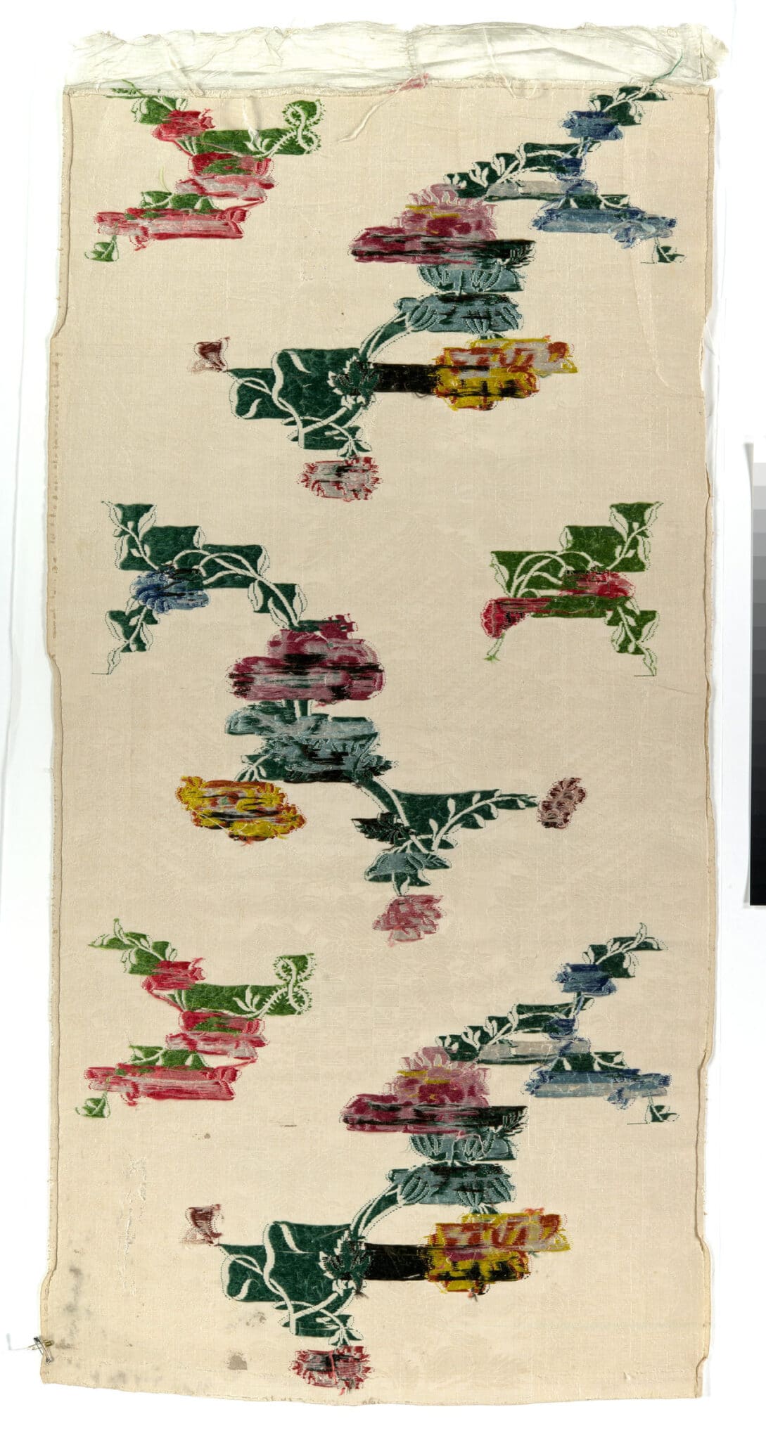 A narrow silk textile panel with multicolored floral motifs on a pale background.