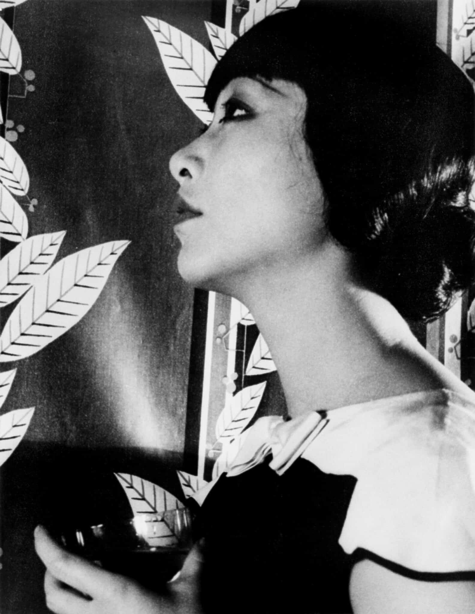 Anna May Wong in profile, holding a patterned fan.