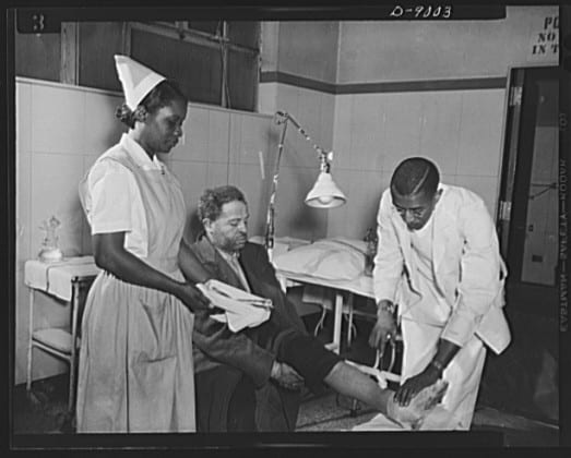 A nurse, a nurse's aide and a physician attend a patient in an operating room.