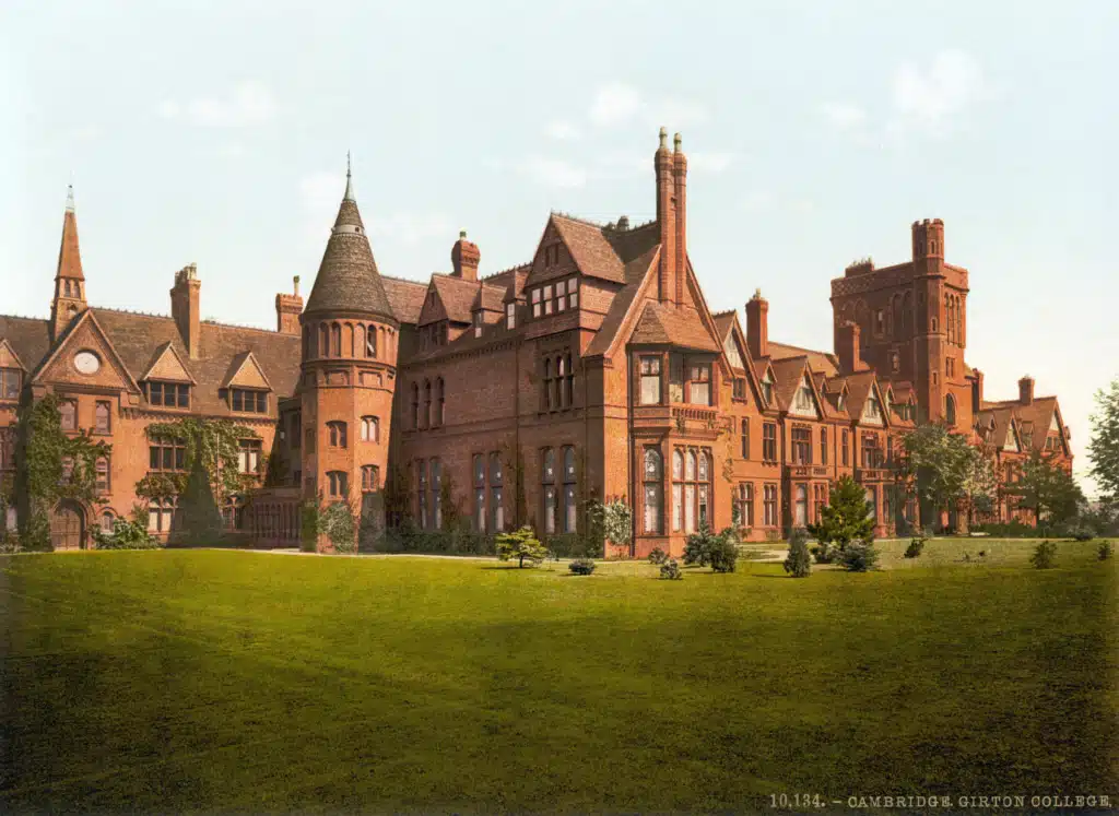 Historic color print of Girton College, with red-brick buildings, a round tower, and a lawn.