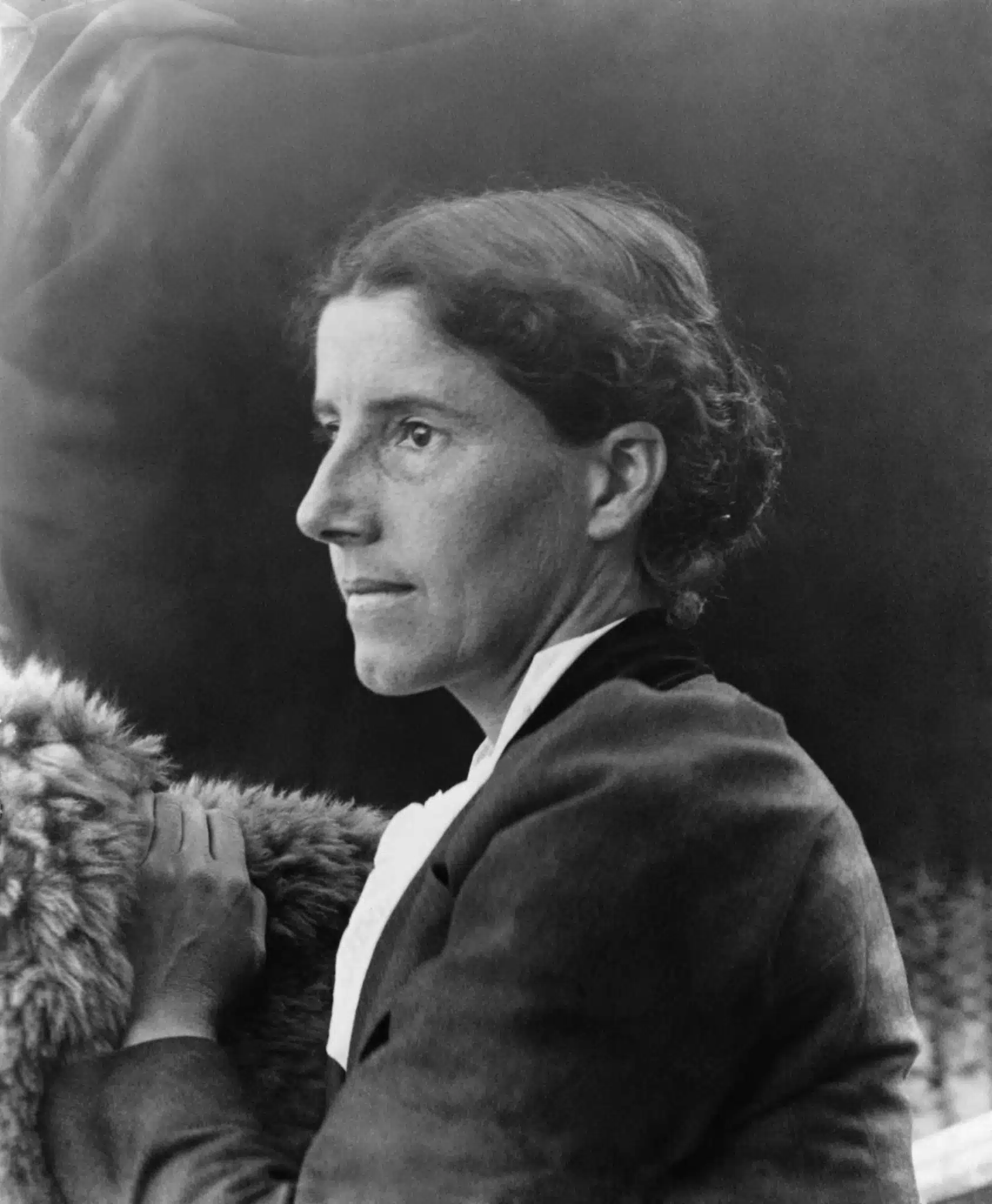 Charlotte Perkins Gilman in profile, with one hand resting on a fur-covered chair.