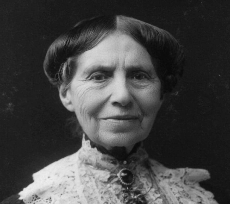 Clara Barton facing the camera, with a lace collar and floral decoration.