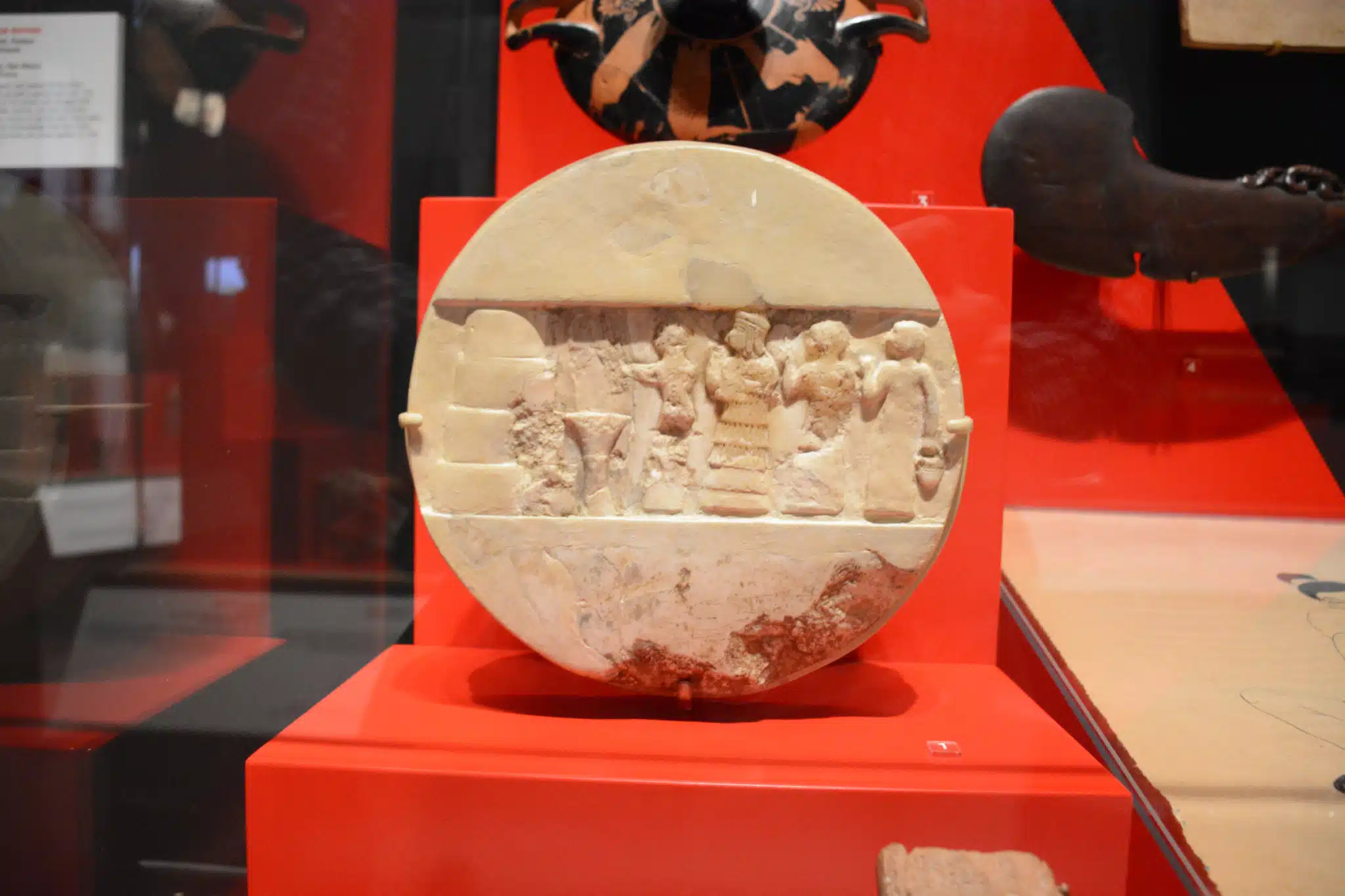 The limestone Disk of Enheduanna displayed in a museum case.