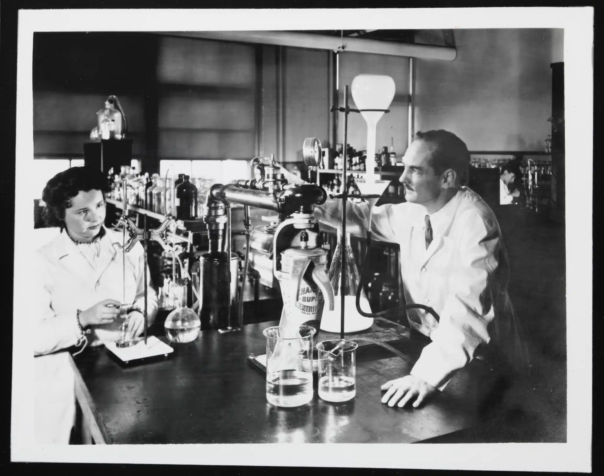Gertrude Elion and George Hitchings sit among laboratory glassware and equipment.