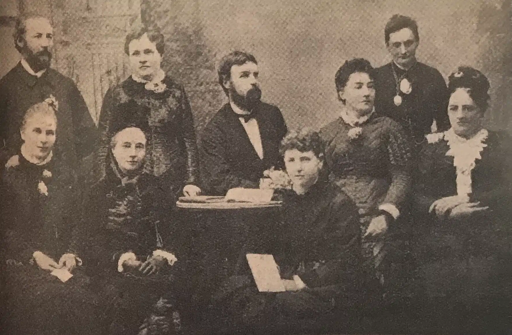 Members of the Victorian Women's Suffrage Society pose around a table.