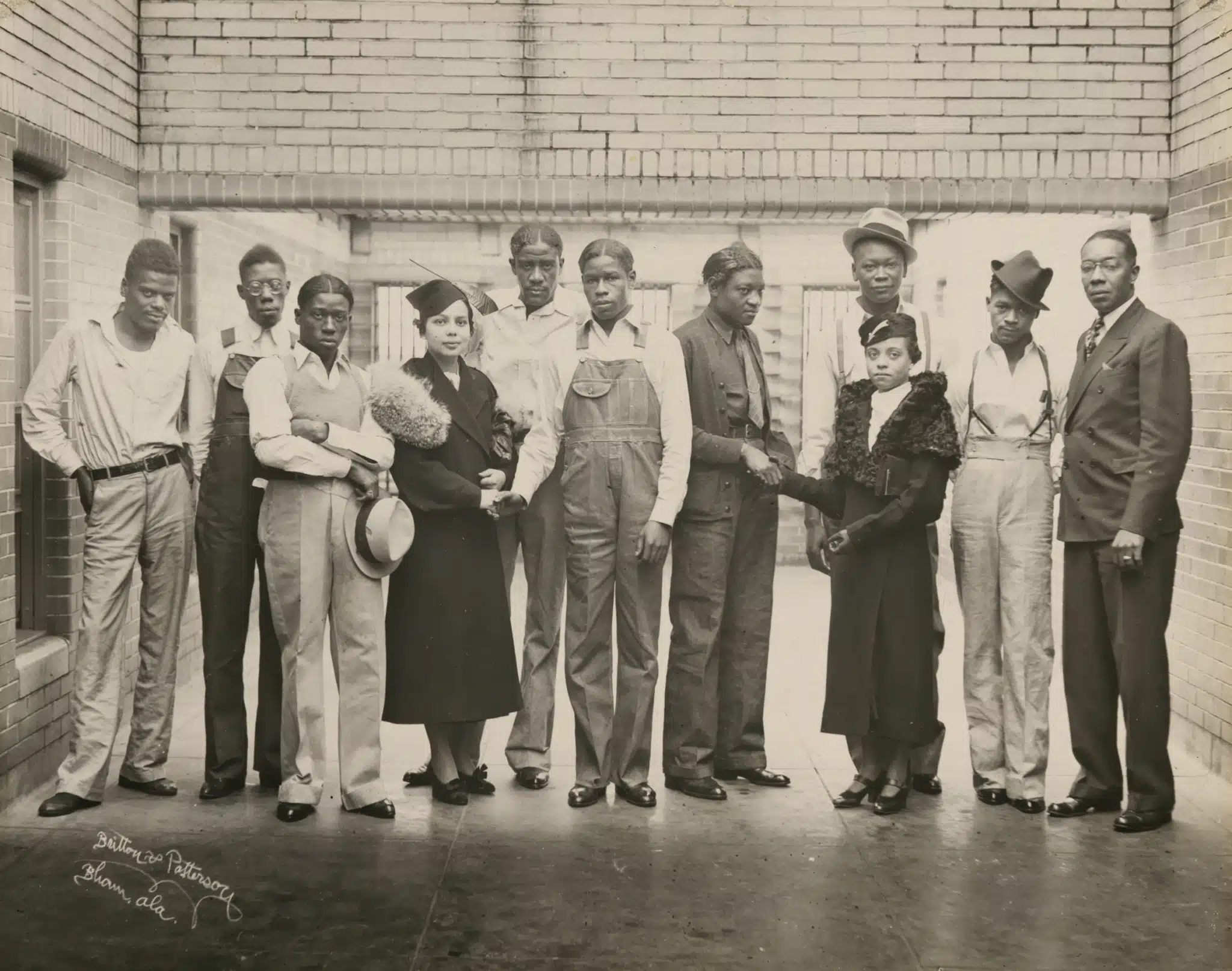 Juanita Jackson Mitchell and the Scottsboro Boys pose together outside a brick building.