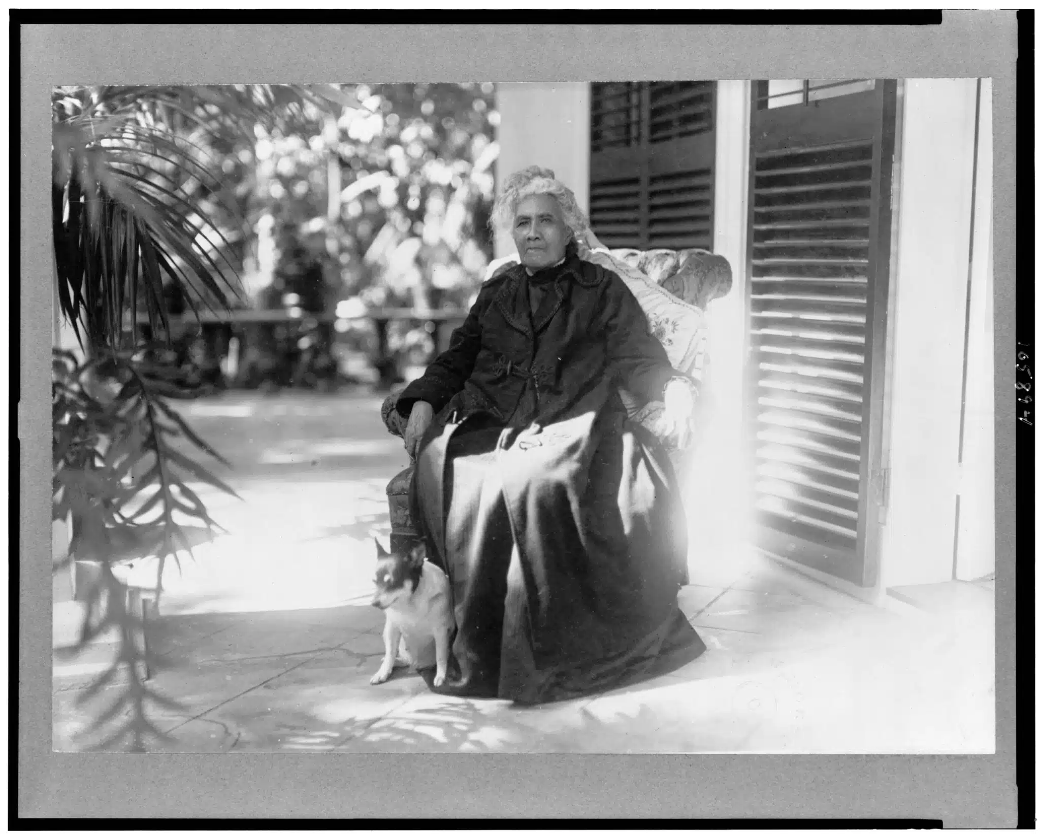 Liliʻuokalani seated outdoors beside a dog.