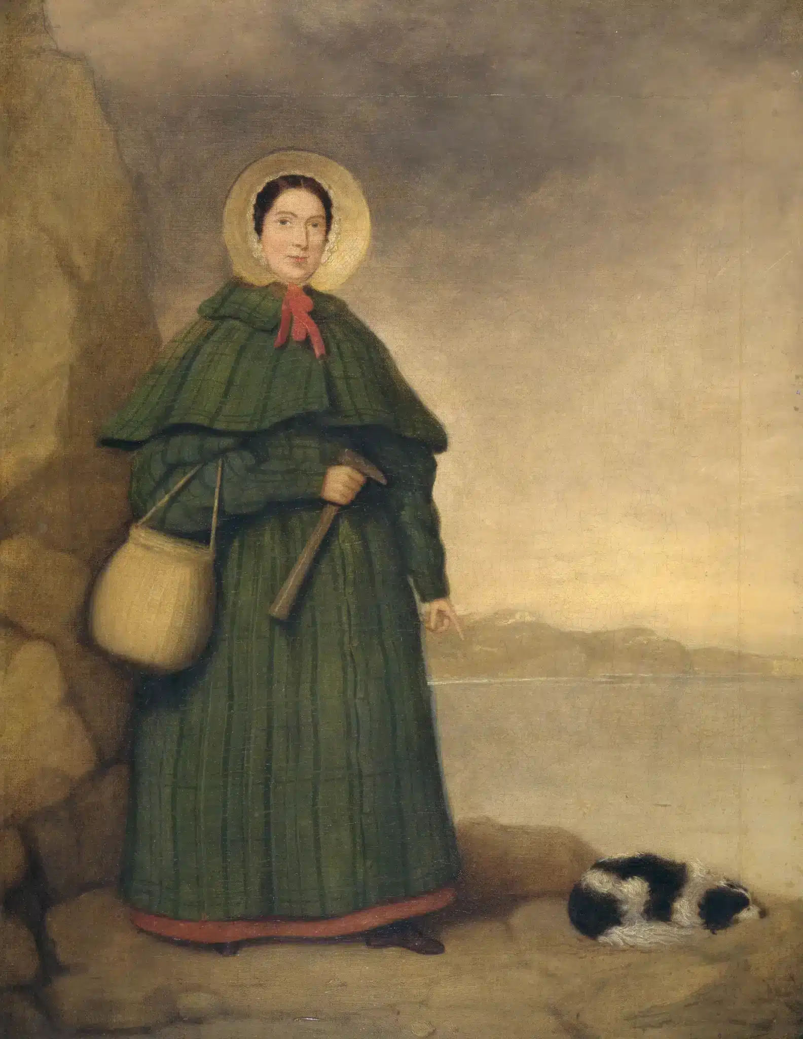 Painting of Mary Anning holding a tool, with her dog beside her and a coastal landscape behind.