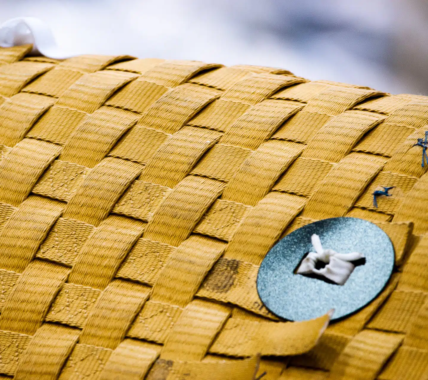 A close-up of woven Kevlar with a metal fastener.