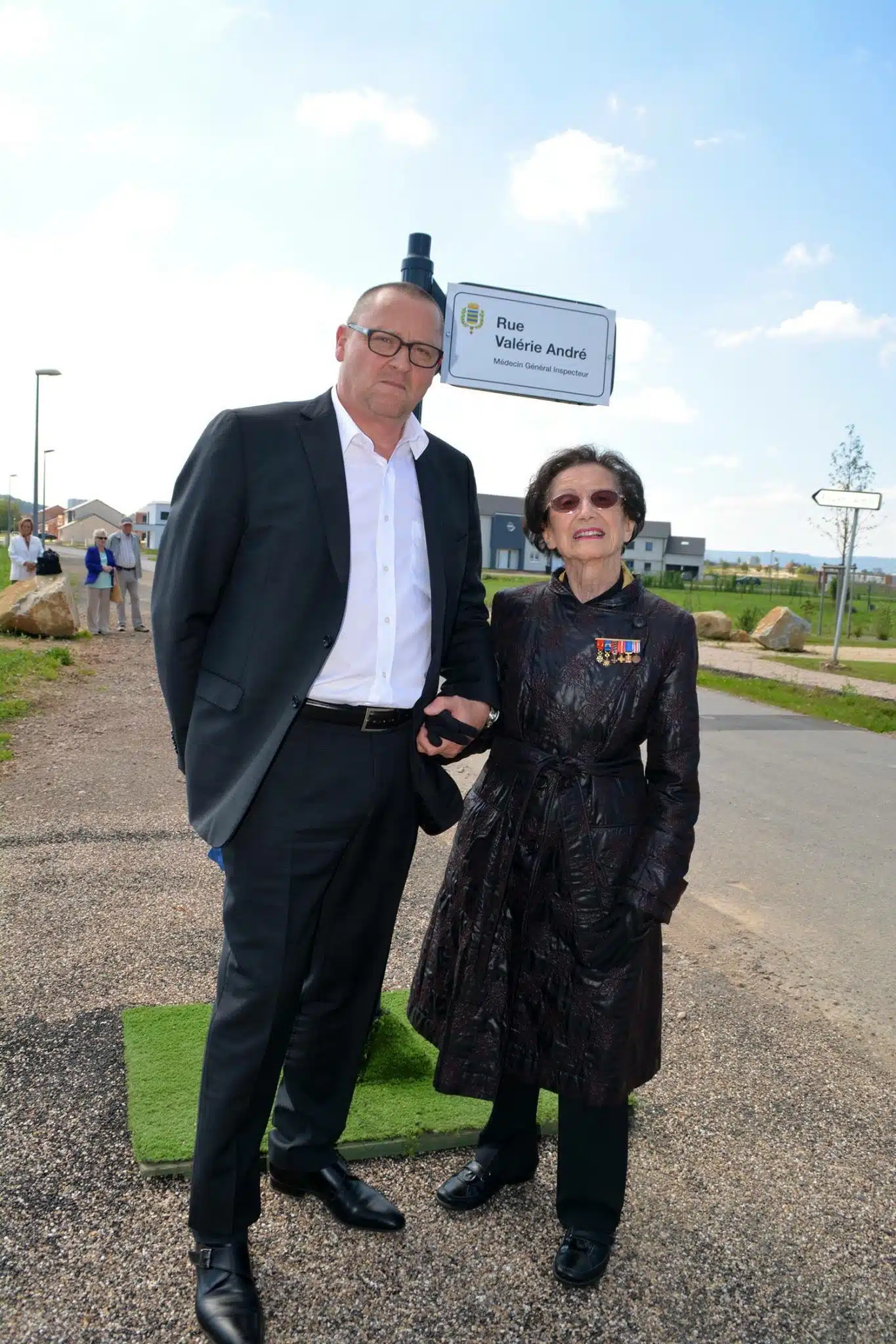 Valérie André stands beside another person at an outdoor street inauguration.